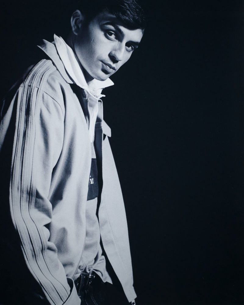 Pedri posing in a pale zipped track jacket and collared shirt against a black backdrop under high-contrast lighting.