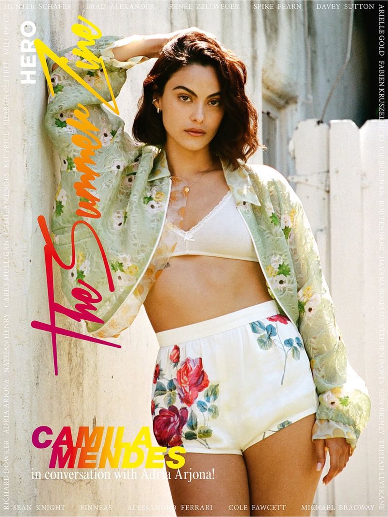 Camila Mendes posing in a green floral jacket, white bralette, and floral shorts for HERO Summer Zine cover.