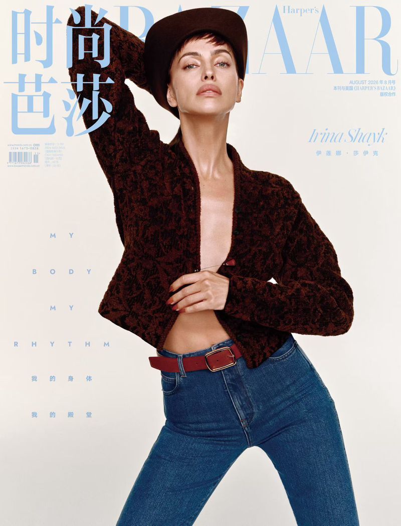 Model Irina Shayk posing in a dark textured jacket and blue denim jeans against an off-white background for Harper's Bazaar China.