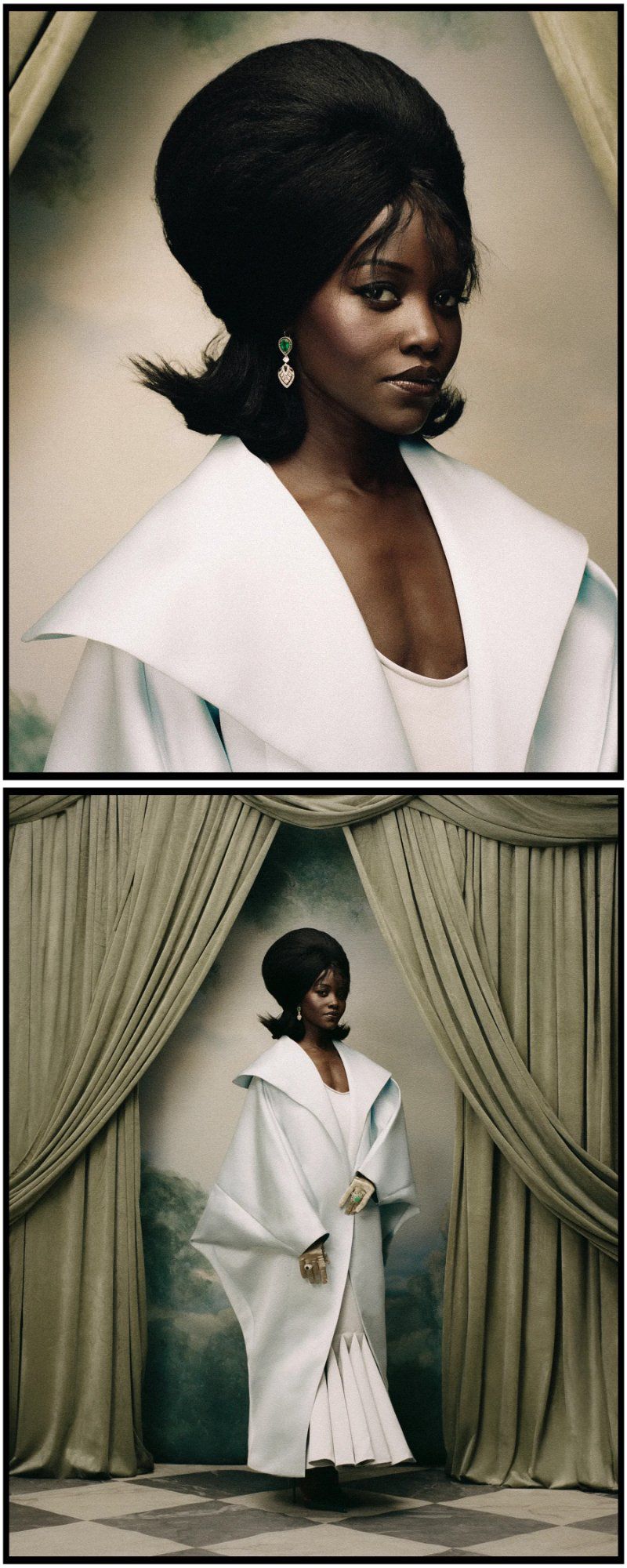 Lupita Nyong'o wearing a white structured coat with a large beehive hairstyle and emerald earrings against draped curtains.