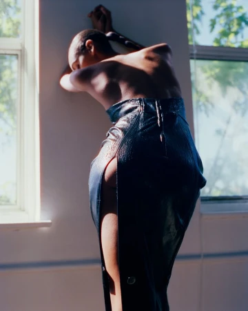 Model Bebe Parnell leaning against a wall wearing a glossy black slit dress from the Supriya Lele Fall Winter 2026 collection.