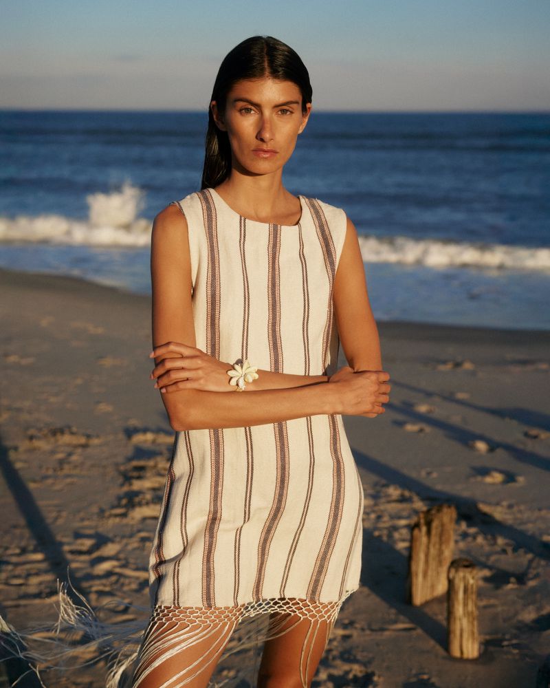 Model wearing a striped dress on a sandy beach at sunset for Alix of Bohemia Summer 26 Campaign