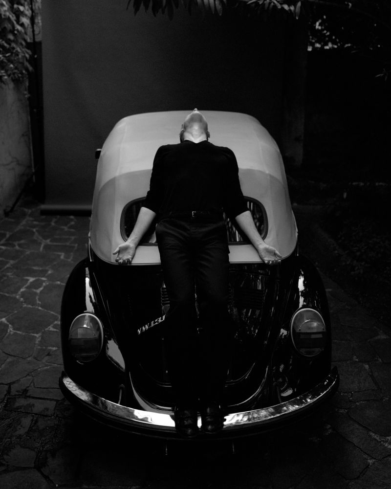 Tom Sturridge reclines backwards across the hood of a vintage Volkswagen Beetle for Replica Man Magazine.