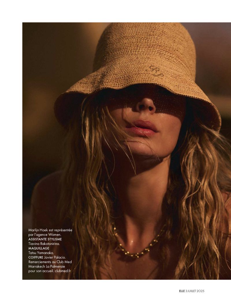 Woman in sun hat with golden jewelry; close-up studio shot with a shallow depth of field and soft lighting.