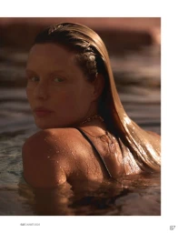 Model Marlijn Hoek immersed in water looking over her shoulder with wet slicked-back hair in warm sunlight.
