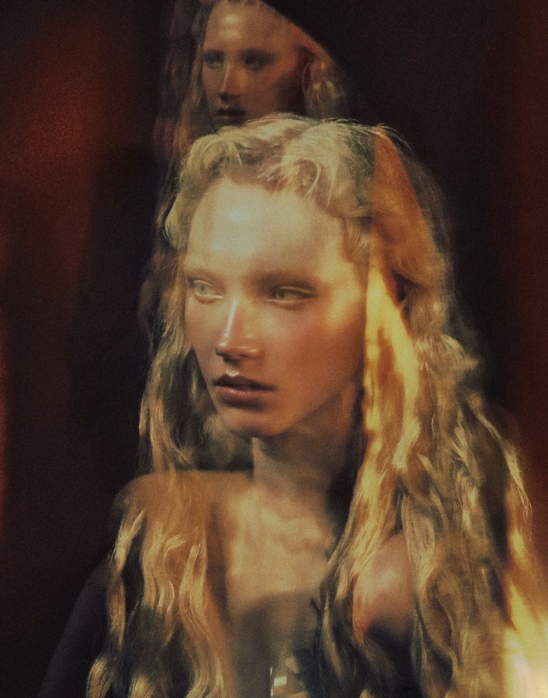 Dreamy editorial portrait of model Ivy Stewart with long blonde hair and warm lighting against a dark backdrop.