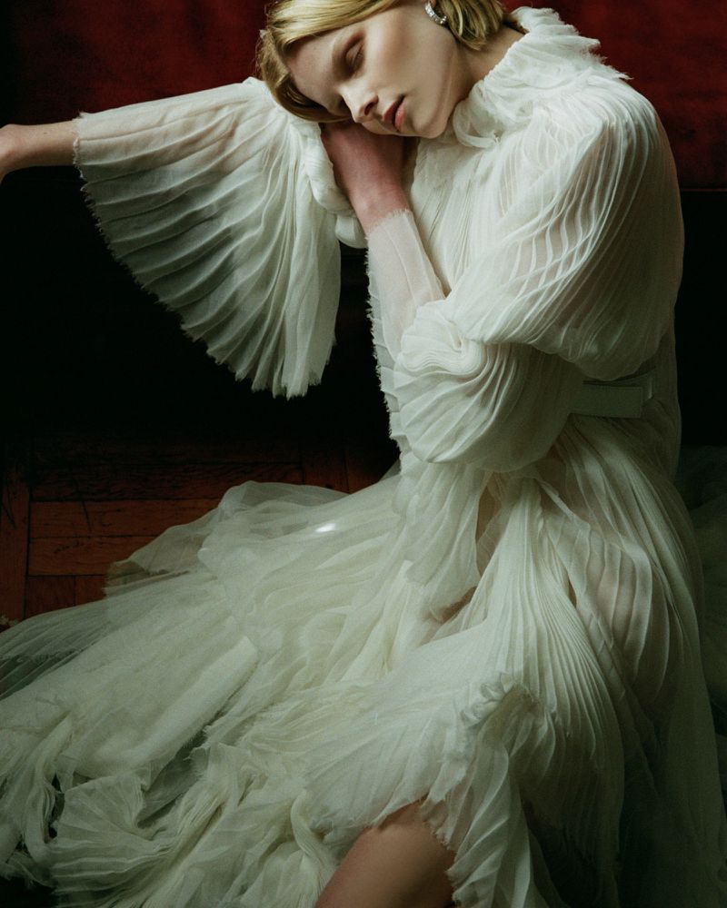A woman with blonde hair in a flowing white dress is featured in a studio shot, eyes closed, with an elegant pose against a dark backdrop.