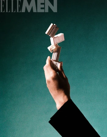 Hand holds a tower of building blocks against a teal background. Fashionable black jacket sleeve is visible in the lower right corner.