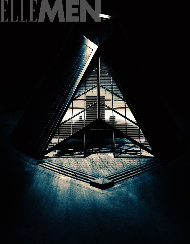 Architectural photograph featuring a triangle-shaped building with glass windows, steps, and a black and blue color scheme.