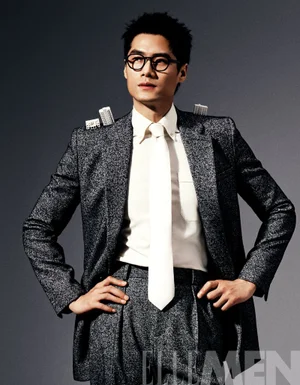 Model Hao Yun Xiang wearing a speckled grey suit, white shirt, and tie with miniature architectural models on his shoulders