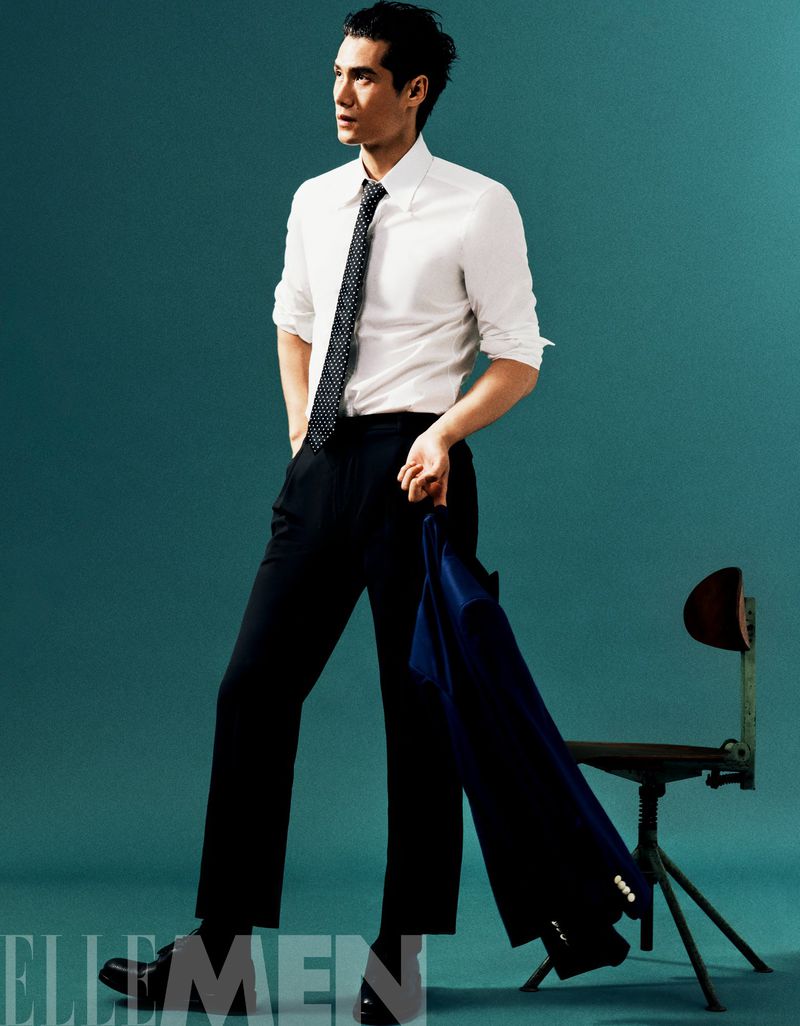 Model Hao Yun Xiang wearing a white shirt and tie holding a jacket against a teal backdrop for Elle Men China
