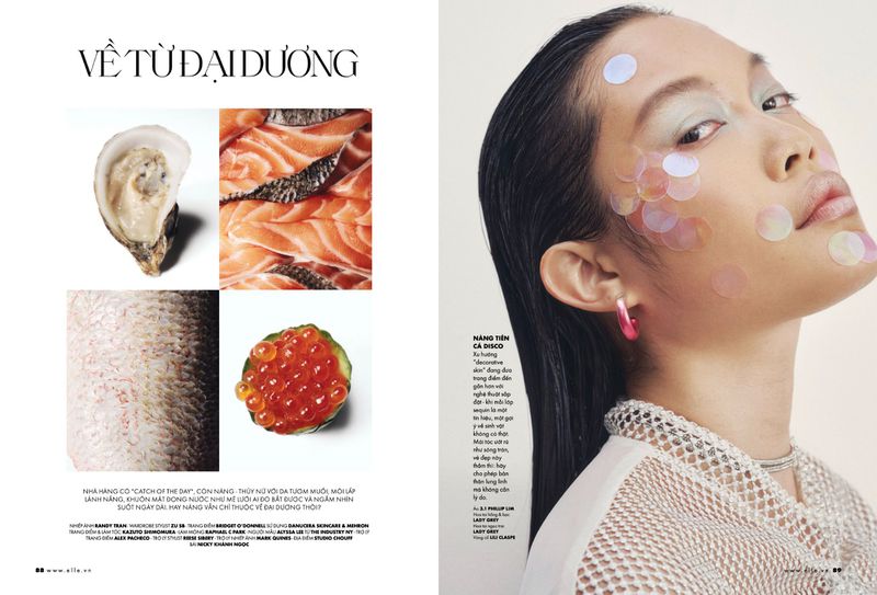 A close-up portrait shot of an Asian woman with iridescent disc makeup, beside oysters, salmon, and caviar from a beauty editorial.