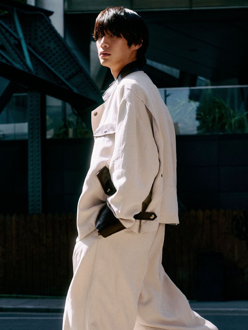 Model Sanggun Lee wearing an oversized off-white tailored jacket and matching trousers on a city street.