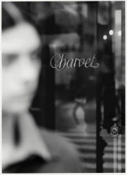 Black and white editorial portrait with a heavily blurred foreground figure and storefront signage reading Charvet