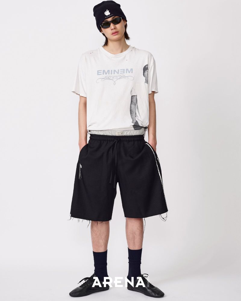Model Jinyeong Pak in an Eminem graphic t-shirt, black beanie, and oversized black shorts against a white backdrop.