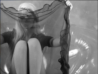 Model Stella Lucia holding a sheer dark fabric across her face for the Beyond Noise project !STELLA!