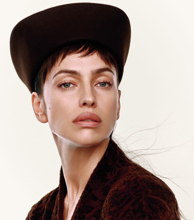 Model Irina Shayk wearing a dark structured hat and textured brown top against a pale background for Harper's Bazaar China.