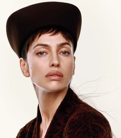 Model Irina Shayk wearing a dark structured hat and textured brown top against a pale background for Harper's Bazaar China.