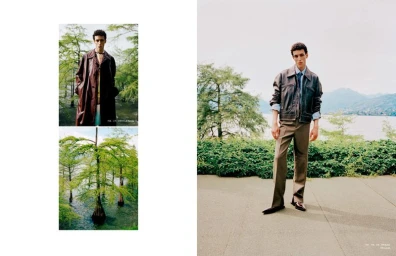 Model standing outdoors near a lake and trees wearing a brown leather jacket and trousers for Arena Homme Plus China.