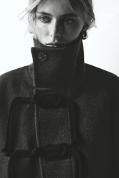 Model Cara Fravel wearing a dark wool coat with toggle closures in a black and white fashion portrait for Tidal Magazine.