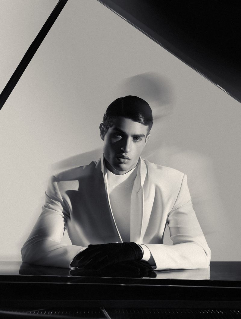 Man wearing a white blazer and black gloves seated at a piano with motion blur background for L'Officiel Hommes Ukraine editorial