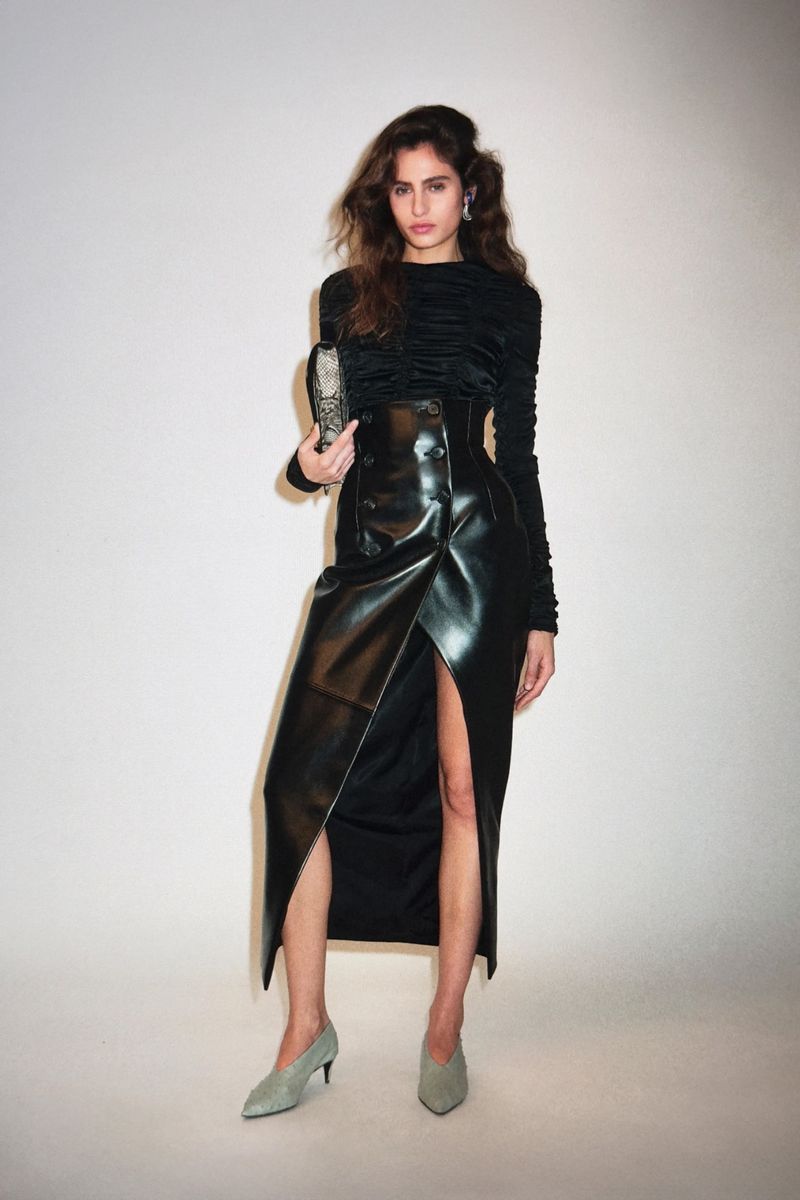 Model Nastassia Legrand in a black ruched top and high-waisted black leather slit skirt with pointed pumps for Khaite Pre-Fall 2026.
