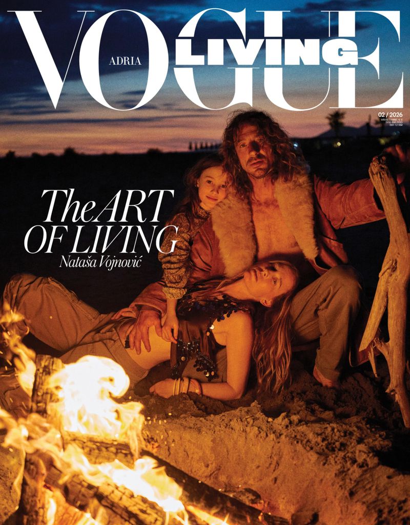Model Nataša Vojnović, a man, and a child seated on a sandy beach beside a blazing campfire on a magazine cover.