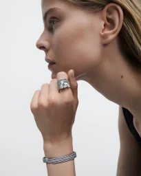Close-up profile of a model wearing a diamond ring and matching bracelet against a plain white background