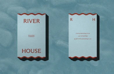 Two powder blue business cards with red serrated edges and serif typography for River House, cast against a blue textured background.