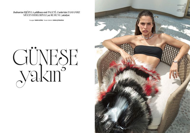 Woman in a black bandeau top and feathered skirt lounging in a wicker chair outdoors