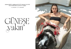 Woman in a black bandeau top and feathered skirt lounging in a wicker chair outdoors