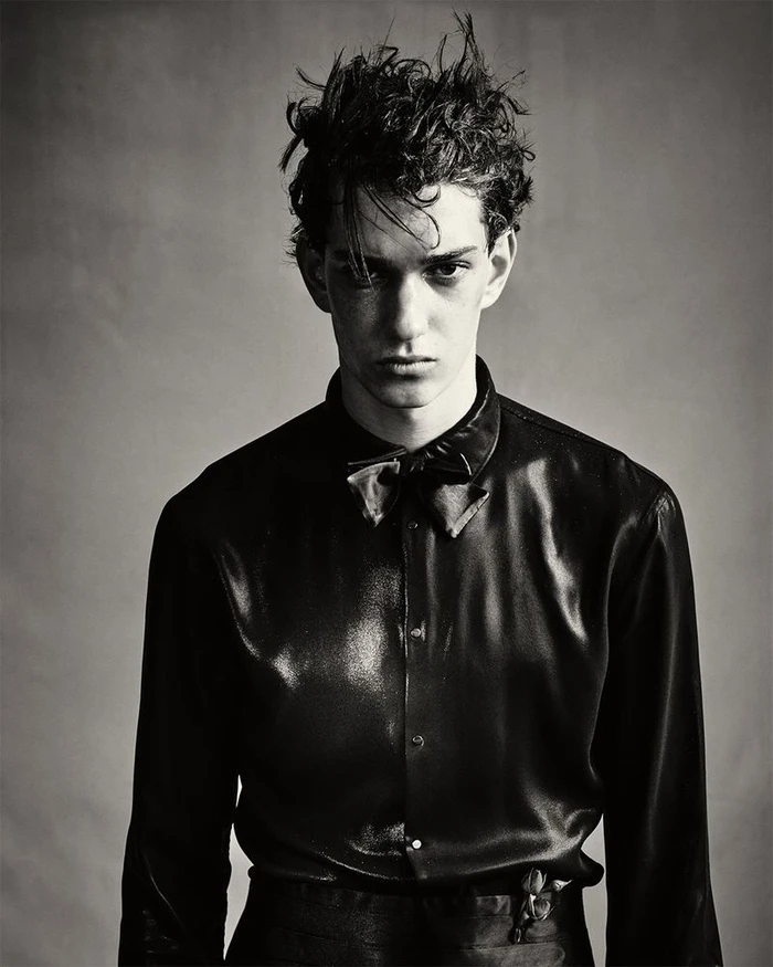 Model Artjom Zagrebaylov in a dark silk button-down shirt and bow tie in a black and white studio portrait.