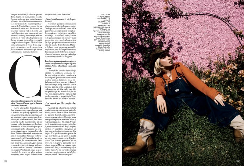 Belinda wearing denim overalls, an orange shirt, and a cowboy hat sitting in grass before a pink wall in Vogue Mexico editorial.