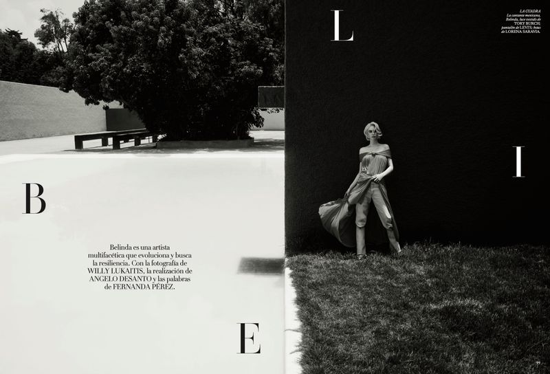 Belinda posing in a draped dress and trousers outdoors against dark architectural walls for Vogue Mexico.