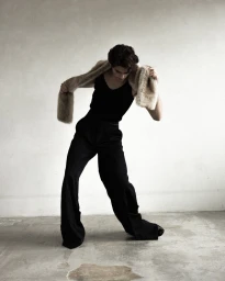 William Franklyn-Miller wearing a black tank top and dark trousers with a faux fur stole in Numero Netherlands editorial photography.