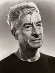 Close-up monochrome portrait of artist Maurizio Cattelan looking to the side in a black crew neck t-shirt.