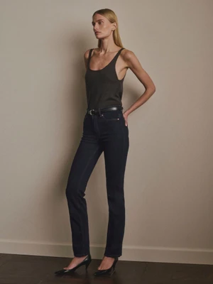 Veronika Vilim in a dark scoop tank top and straight-leg dark denim jeans standing against a neutral studio wall.