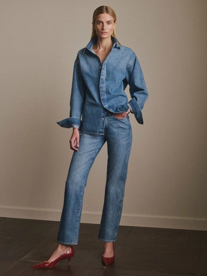 Veronika Vilim wearing an oversized denim shirt and matching straight-leg jeans with red pointed heels for DL1961.