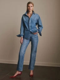 Veronika Vilim wearing an oversized denim shirt and matching straight-leg jeans with red pointed heels for DL1961.