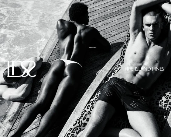 Black and white image of three men in swimsuits lounging on wooden planks by a pool, with the text 'Fire Island Pines'.