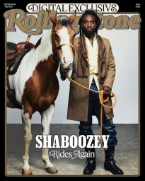 Musician Shaboozey standing beside a saddled brown and white pinto horse holding a lead rope on a Rolling Stone magazine cover.