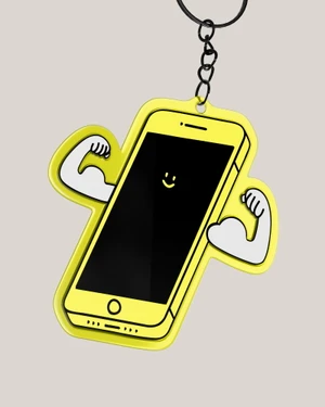 Yellow smartphone keychain with cartoon muscular flexing arms and a smiley face on a black screen, suspended from a metal keyring.