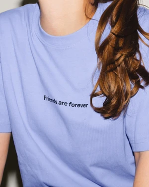 Model wearing a lavender crewneck t-shirt printed with Friends are forever text across the chest.