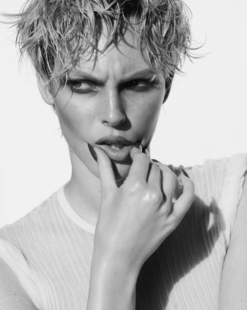 Black and white portrait of Vittoria Ceretti with short tousled hair, touching her lip against a white background for Vogue Italia.