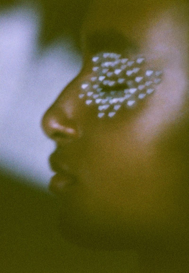 Close-up shot of an African American adult female with decorative heart-shaped embellishments around her eye, fashion beauty shot.