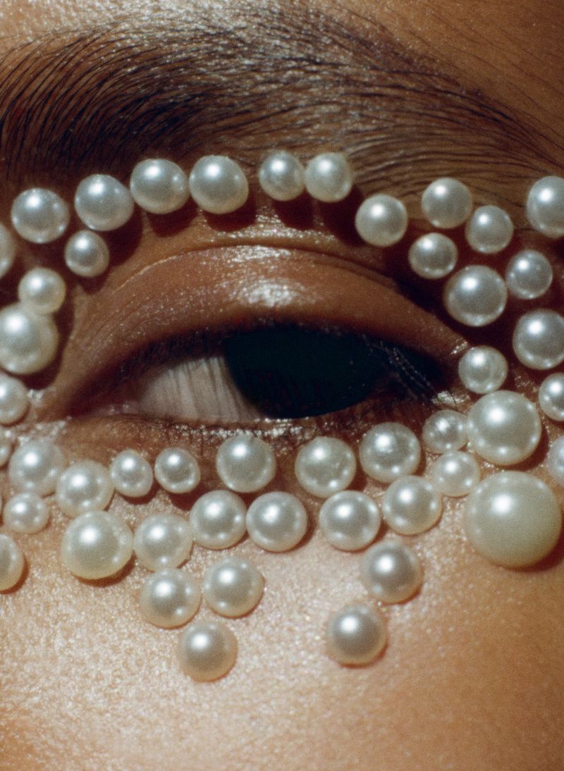 Close-up shot of a human eye adorned with shimmering white pearls, creating a unique and artistic eye makeup look.