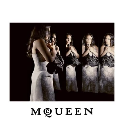 Paloma Elsesser in a white lace dress reflected in mirrors against a black backdrop for McQueen Fall 2026.