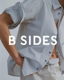 Model wearing a rolled-sleeve striped button-up shirt and light trousers with B SIDES typography overlay.
