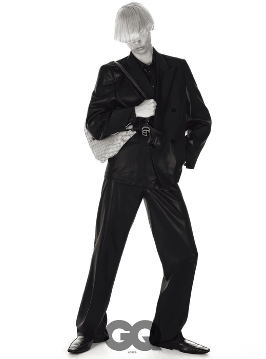 Model Taemin Park posing in a black double-breasted suit and shoulder bag with blunt blonde bangs against a pure white backdrop.