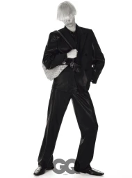 Model Taemin Park posing in a black double-breasted suit and shoulder bag with blunt blonde bangs against a pure white backdrop.